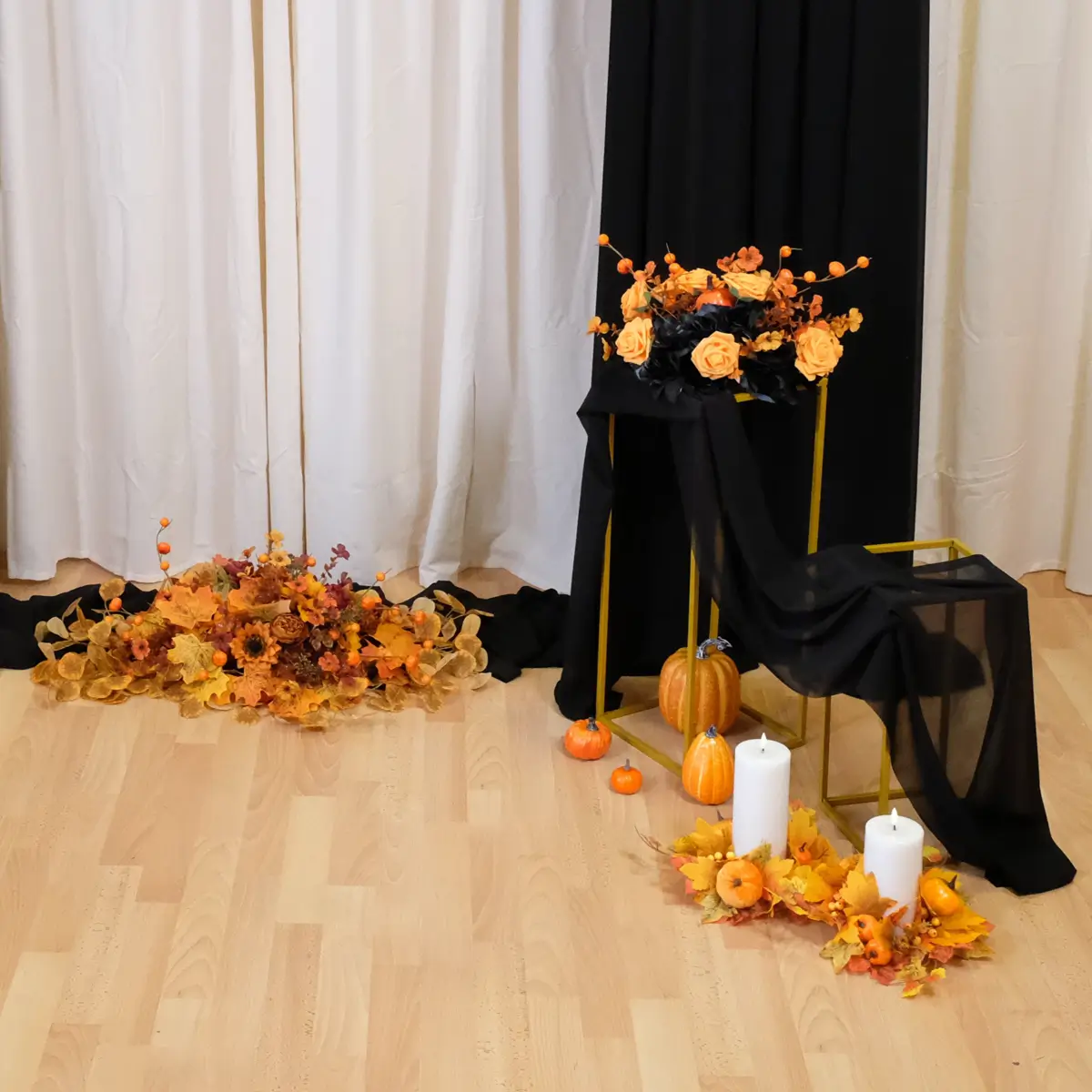 Backdrop med sort stof, orange blomsterdeko, græskar, firkant stativer og lyskranse