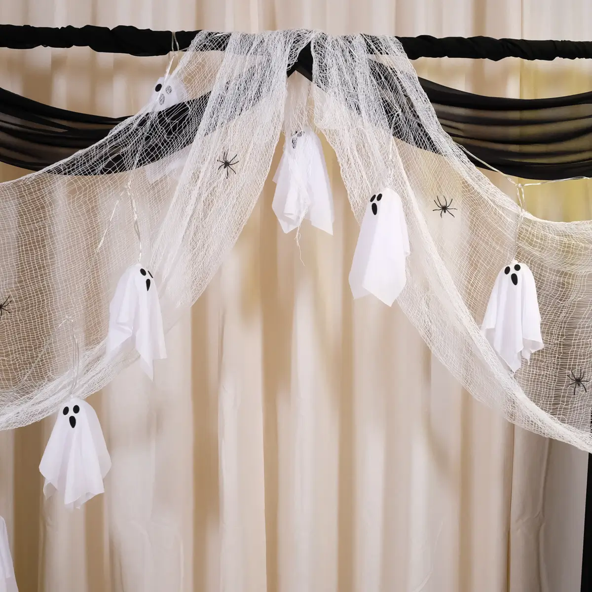 Halloween pyntet backdrop med sort stof, spindelvæv, edderkopper, sorte roser og lyskæde med små spøgelser