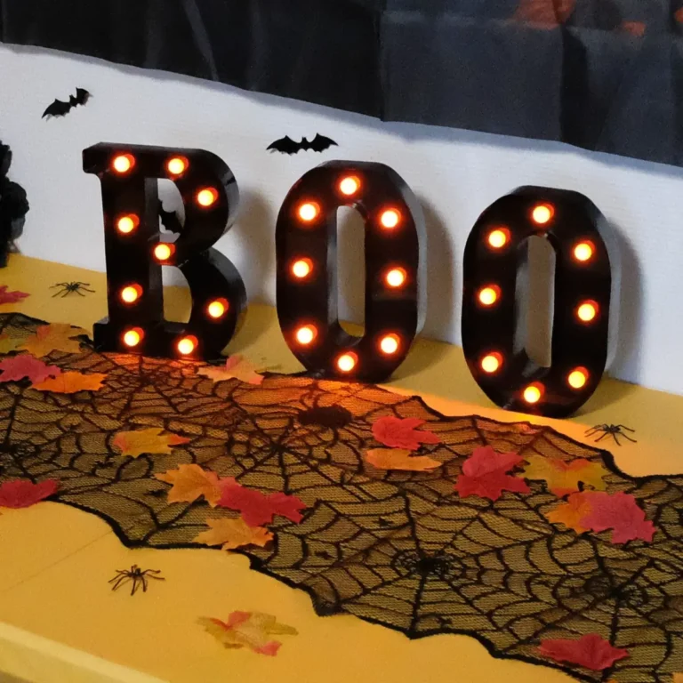 Halloween pynt med happy halloween banner, buffetbord med LED bloklys, LED BOO bogstaver i sort og orange, spindelvævs bordløber, blade og græskar