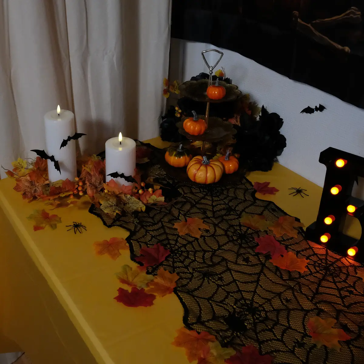Halloween pyntet buffetbord med LED bloklys, LED BOO bogstaver i sort og orange, spindelvævs bordløber, blade, edderkopper, flagermus og græskar
