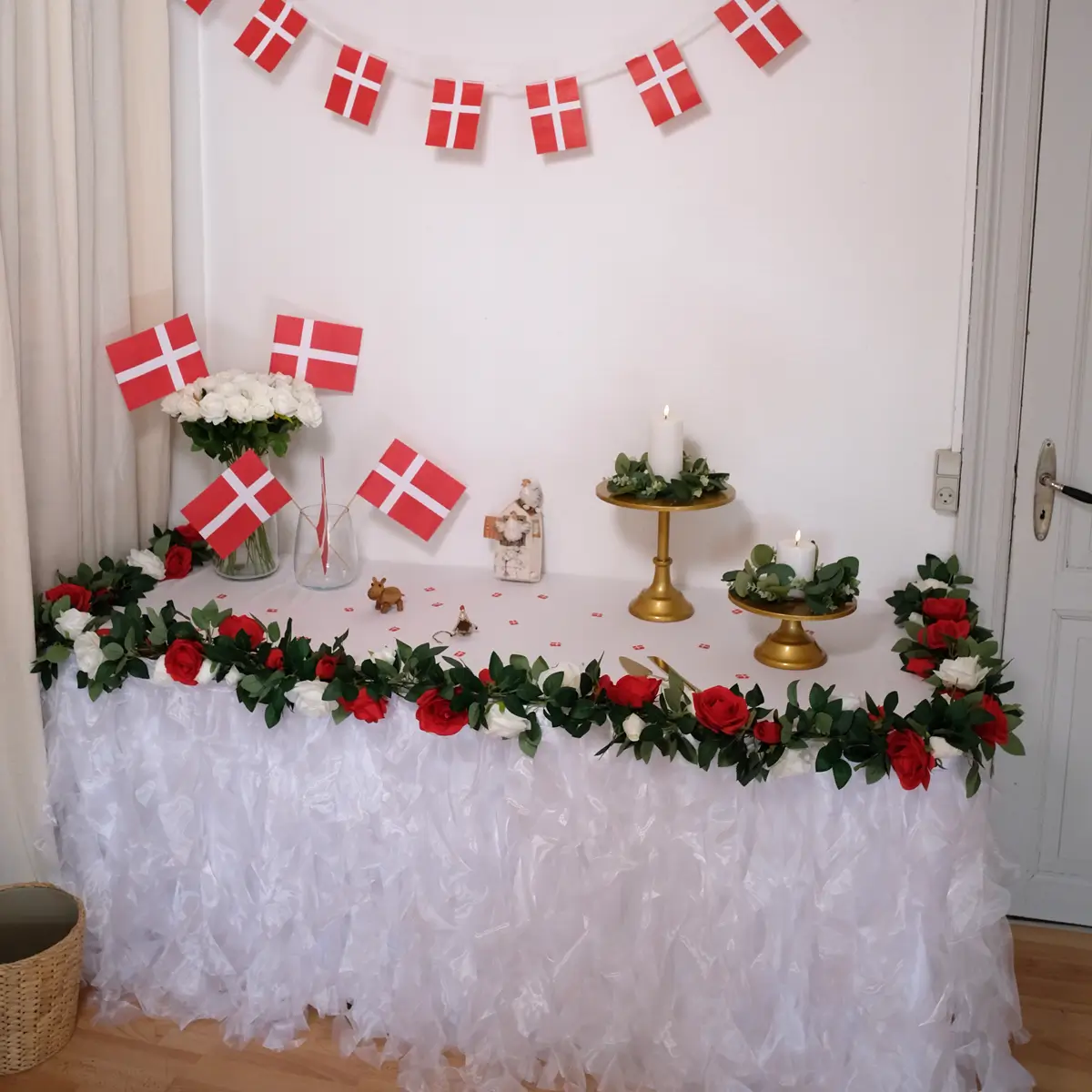 Gavebord med hvid tyl bordnederdel, røde og hvide rosenranker, LED stearinlys, eukalyptus blad kranse, gyldne kagestativer, guldfarvet kageskæringssæt, hvide roser og flag - fødselsdag - workcase