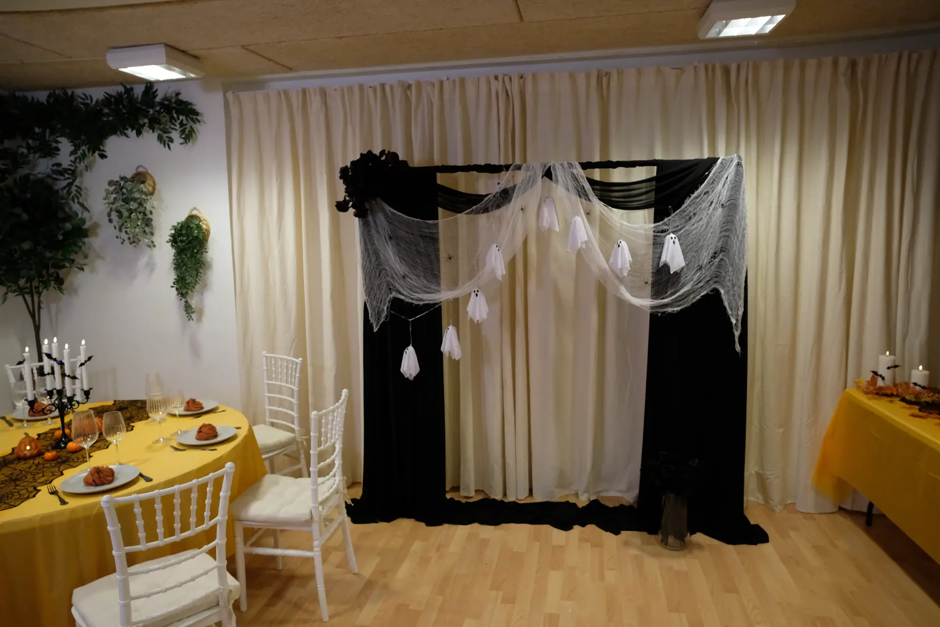 Halloween pyntet backdrop med sort stof, spindelvæv, edderkopper, sorte roser og lyskæde med små spøgelser