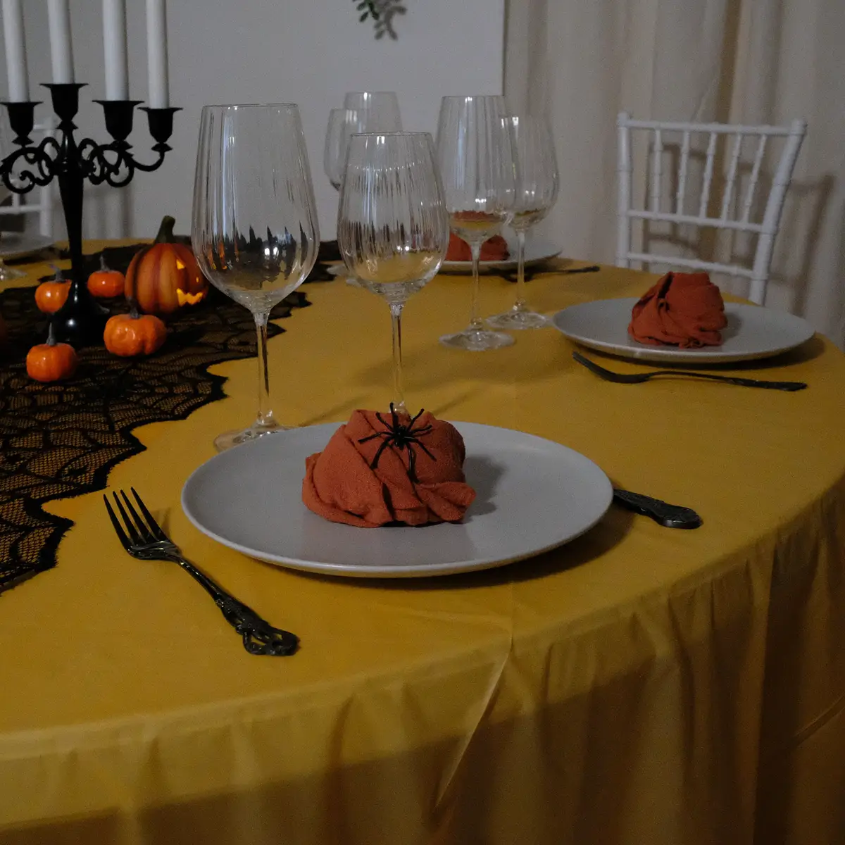 Halloween borddækning med sort bestik med mønster, grå tallerkner , orange stofservietter, rillede glas og halloweenpynt