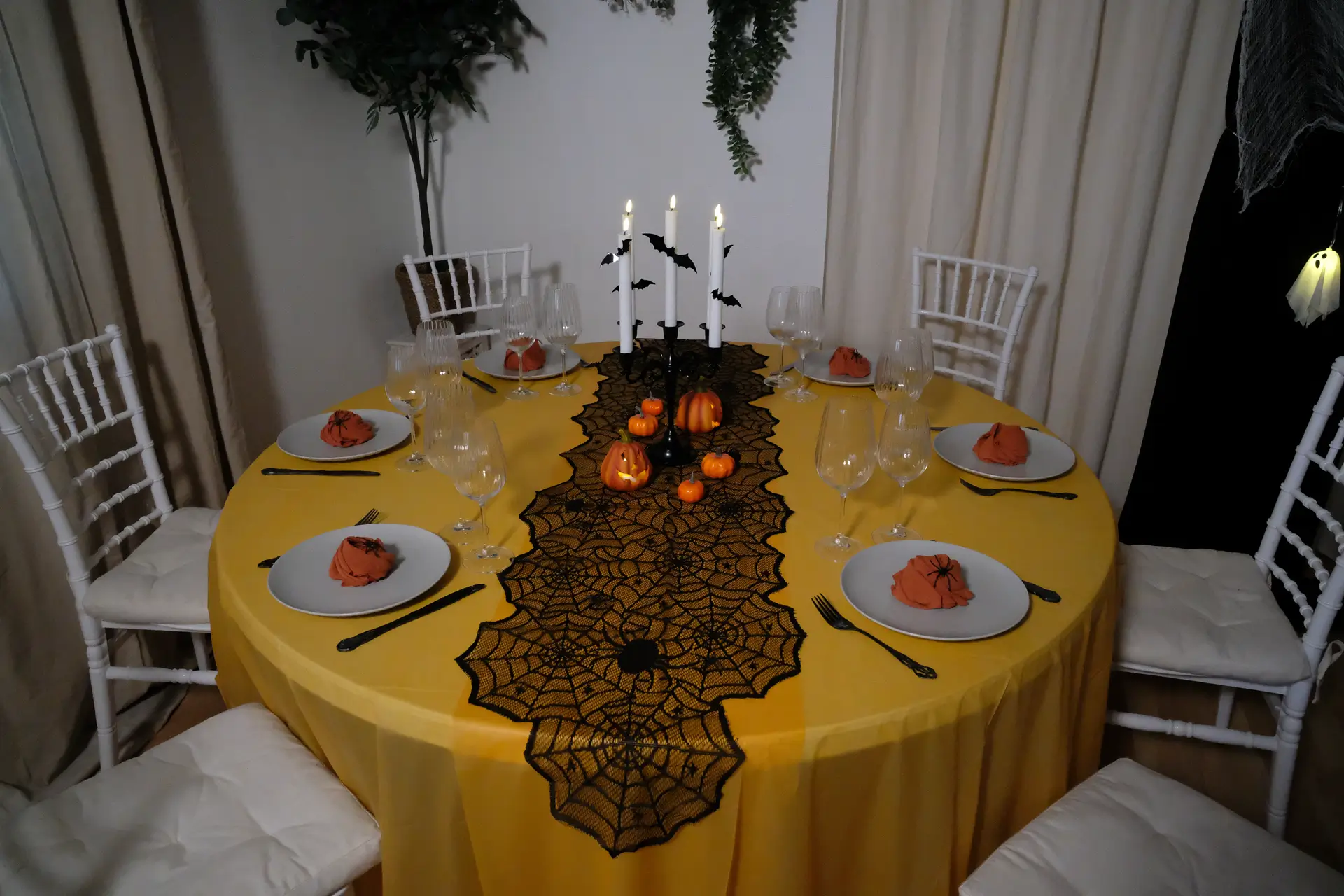 Halloween borddækning med sort bestik med mønster, grå tallerkner , orange stofservietter, rillede glas, LED-lys, sort lysestage, græskar og halloweenpynt