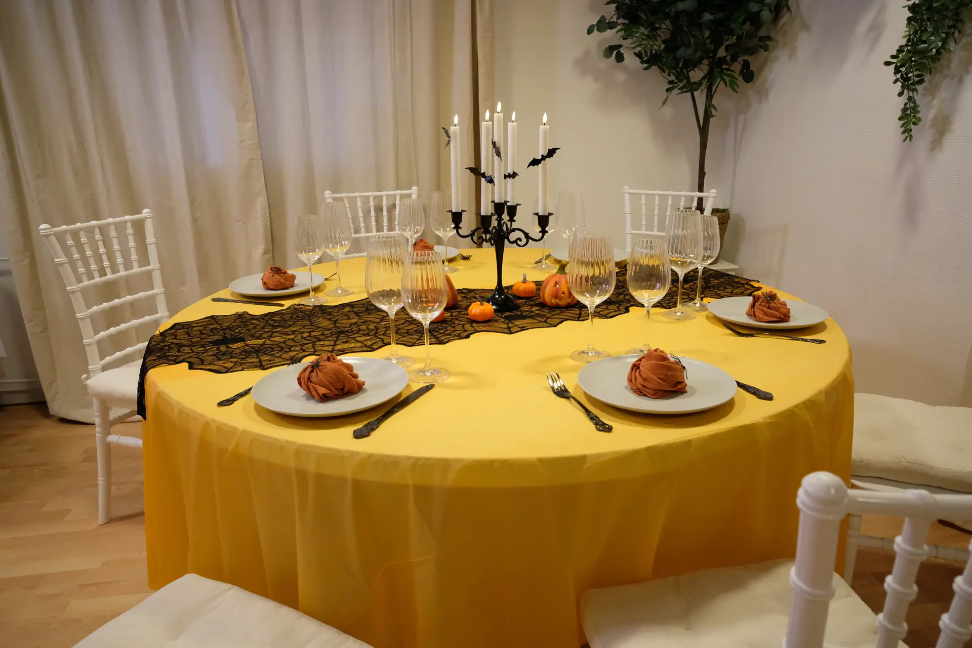 Halloween borddækning med sort bestik med mønster, grå tallerkner , orange stofservietter, rillede glas, LED-lys, sort lysestage, græskar og halloweenpynt