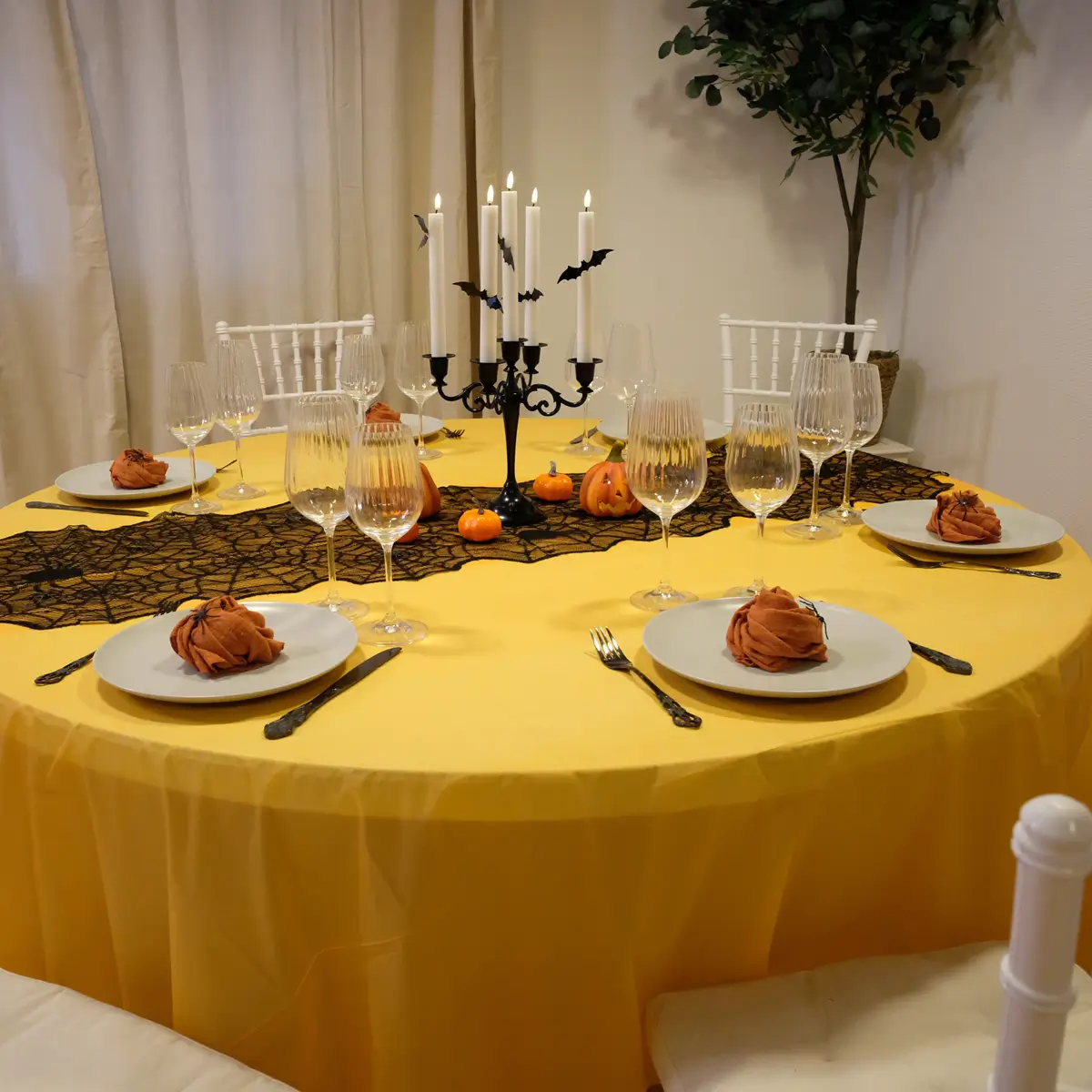 Halloween borddækning med sort bestik med mønster, grå tallerkner , orange stofservietter, rillede glas, LED-lys, sort lysestage, græskar og halloweenpynt