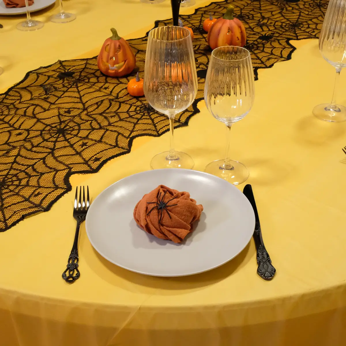 Halloween borddækning med sort bestik med mønster, grå tallerkner , orange stofservietter, rillede glas og halloweenpynt