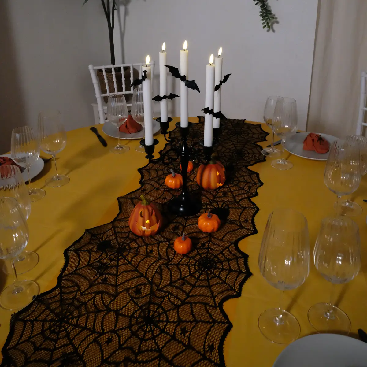 Halloween borddækning med sort bestik med mønster, grå tallerkner , orange stofservietter, rillede glas, LED-lys, sort lysestage, græskar og halloweenpynt
